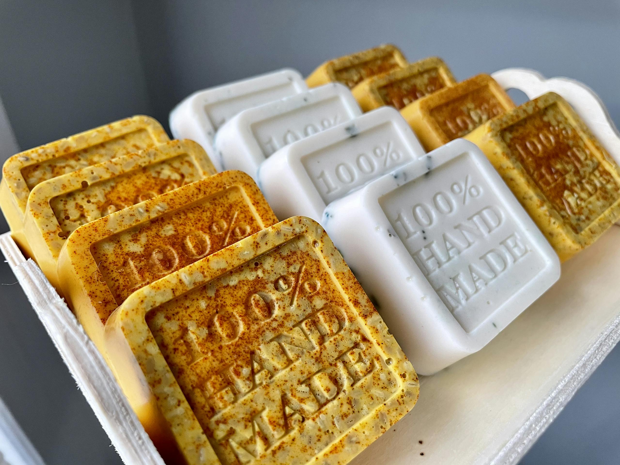 Handmade artisan soaps with '100% Hand Made' text, showcasing organic ingredients and craftsmanship.